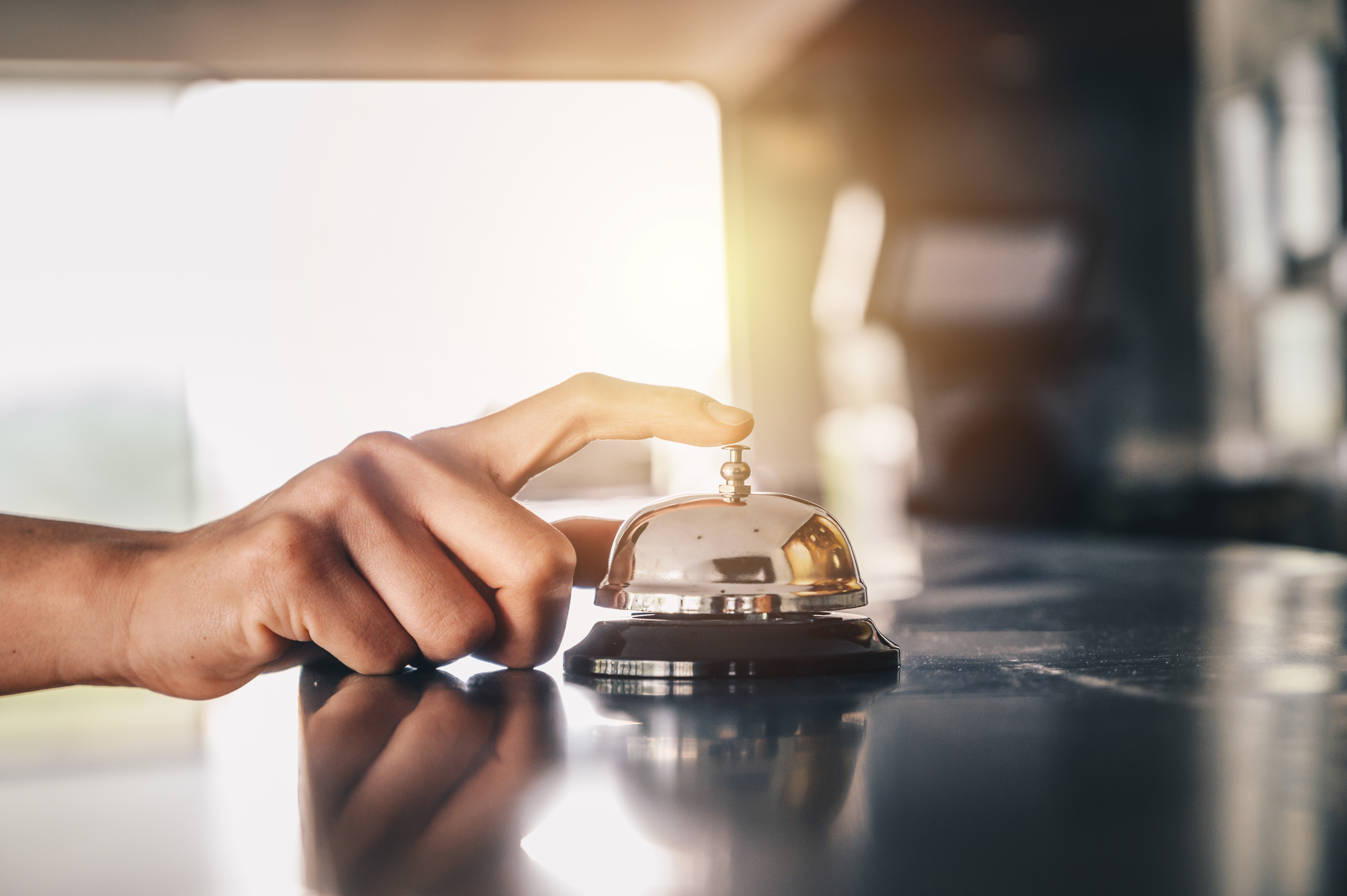 Close-up of someone hand trying to call hotel reception by ringing front desk bell. Hotel bell is normally use to call staff service and staff can help guests with any queries that they may have.