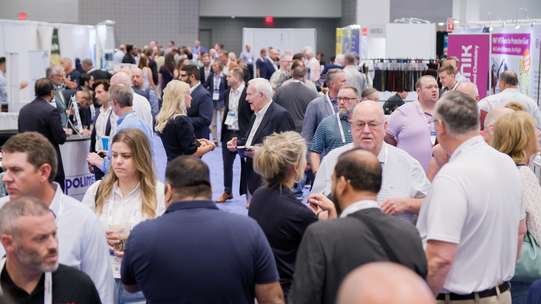 Visitors examining fabric samples and textiles at a booth during Texworld New York